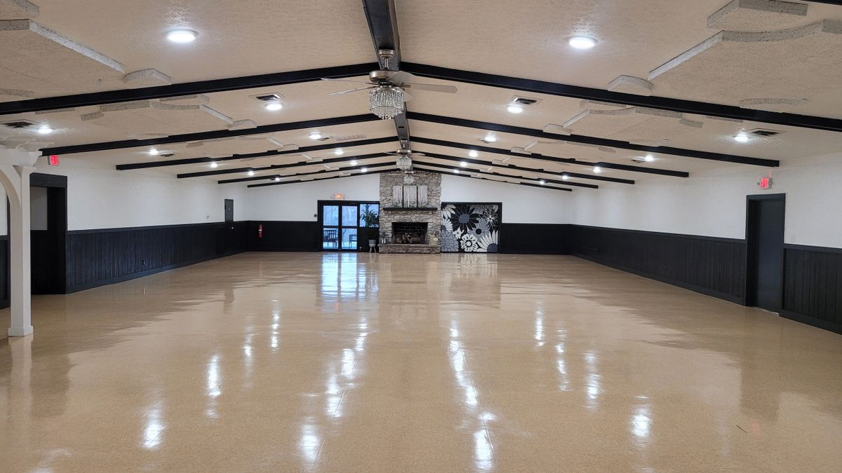 The spacious main hall with vaulted ceilings, stone fireplace, and polished floors